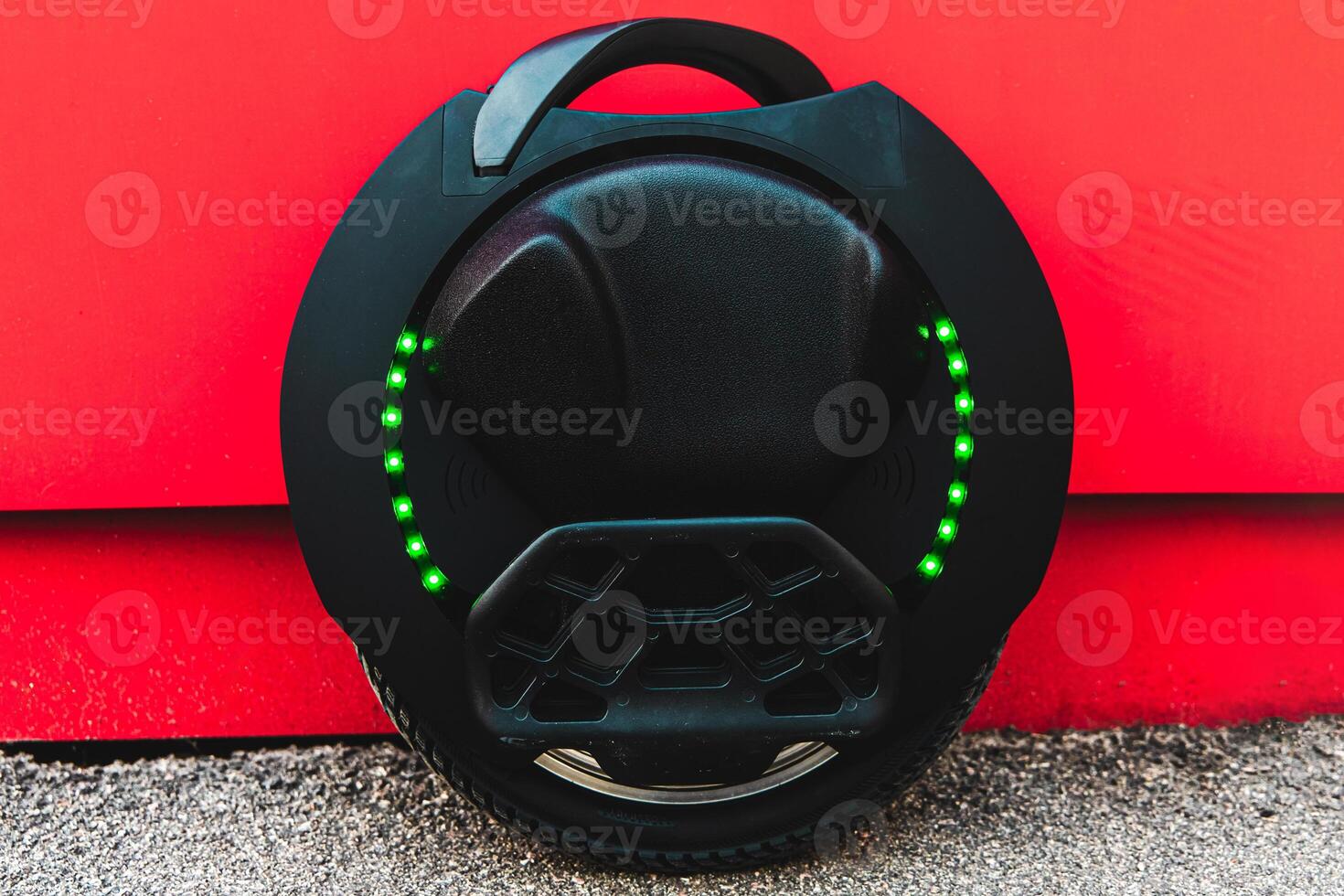 Innovative electric unicycle parked against a vibrant red wall during daytime photo