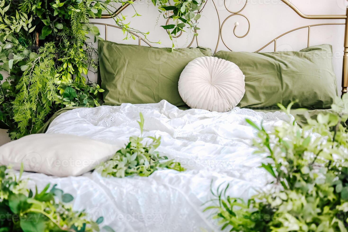 Cozy bed adorned with greenery and soft linens creating a serene atmosphere in a bedroom photo