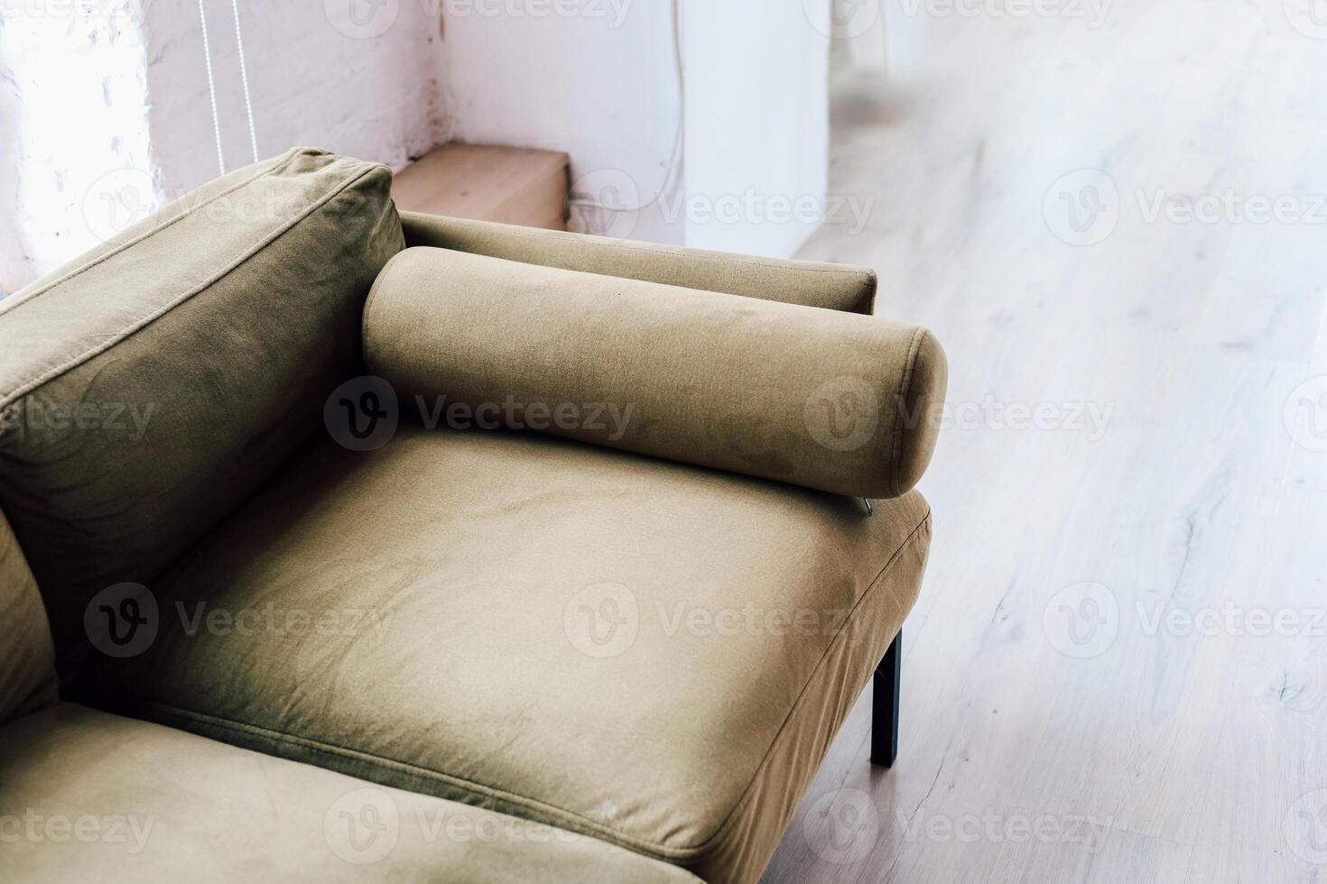 Modern olive green sofa with a unique cylindrical armrest displayed in bright interior space photo