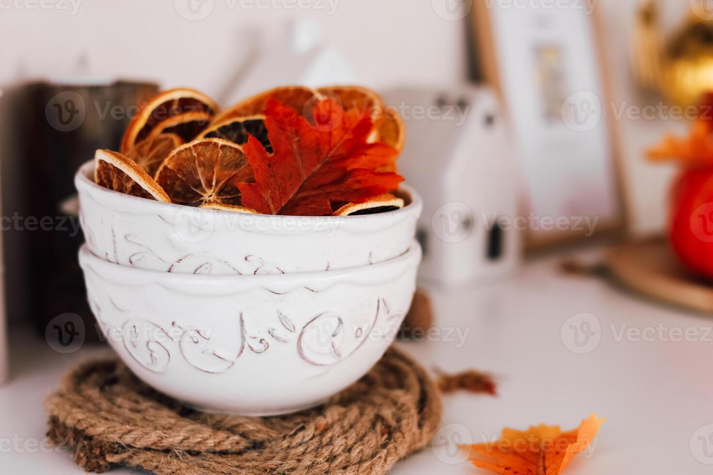 Decorative bowls with dried orange slices and autumn leaves on a rustic cozy table photo