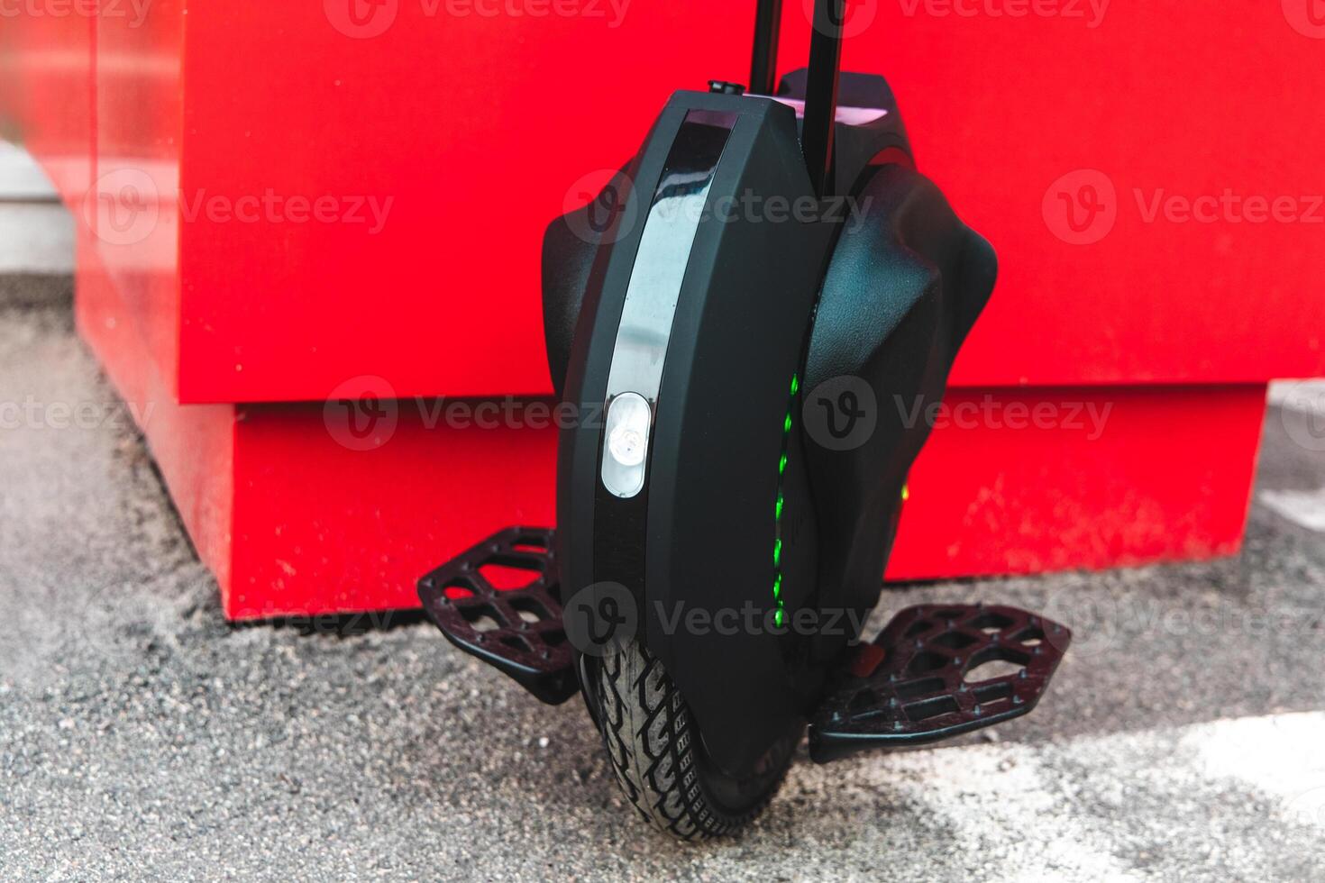 Electric unicycle parked next to a bright red wall in a modern urban setting photo
