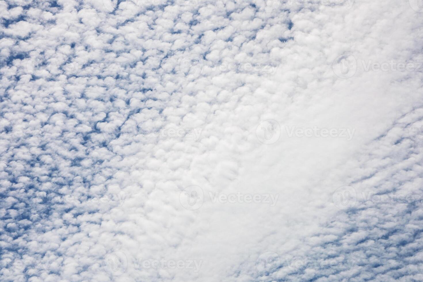 Fluffy clouds create a textured sky over a tranquil landscape during the late afternoon hours photo