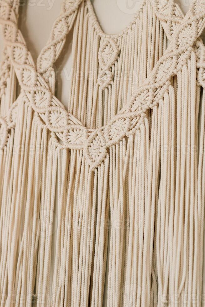 Macrame wall hanging displaying intricate patterns and textures in a light beige color photo