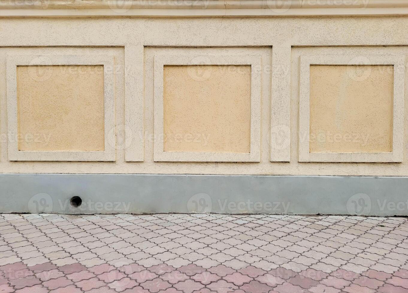 A wall with decorative beige bark beetle plaster and part of the paving slabs. photo
