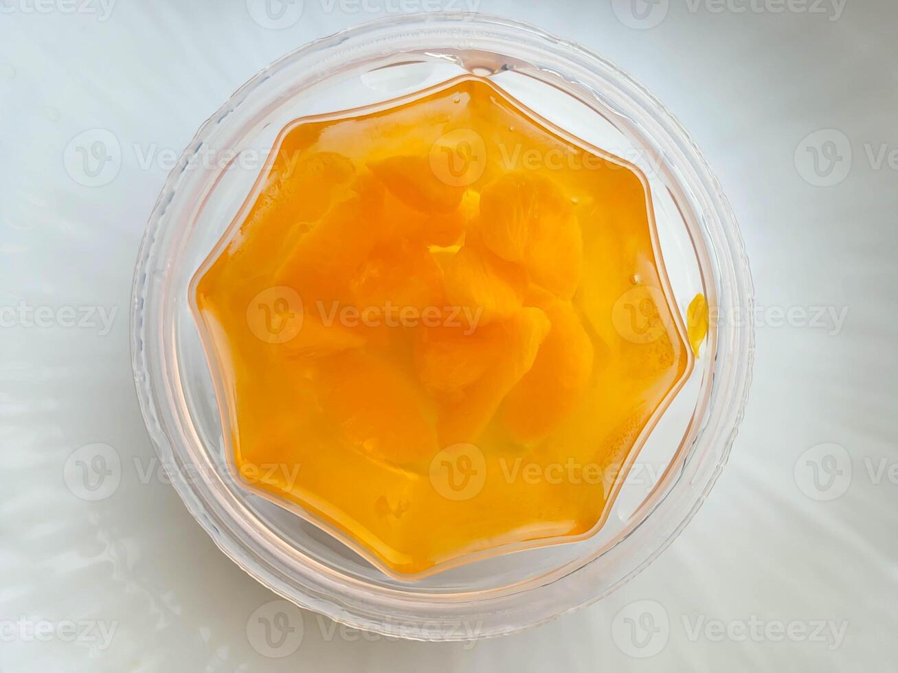 Mandarin orange slices in jelly on a plate on a white table. photo