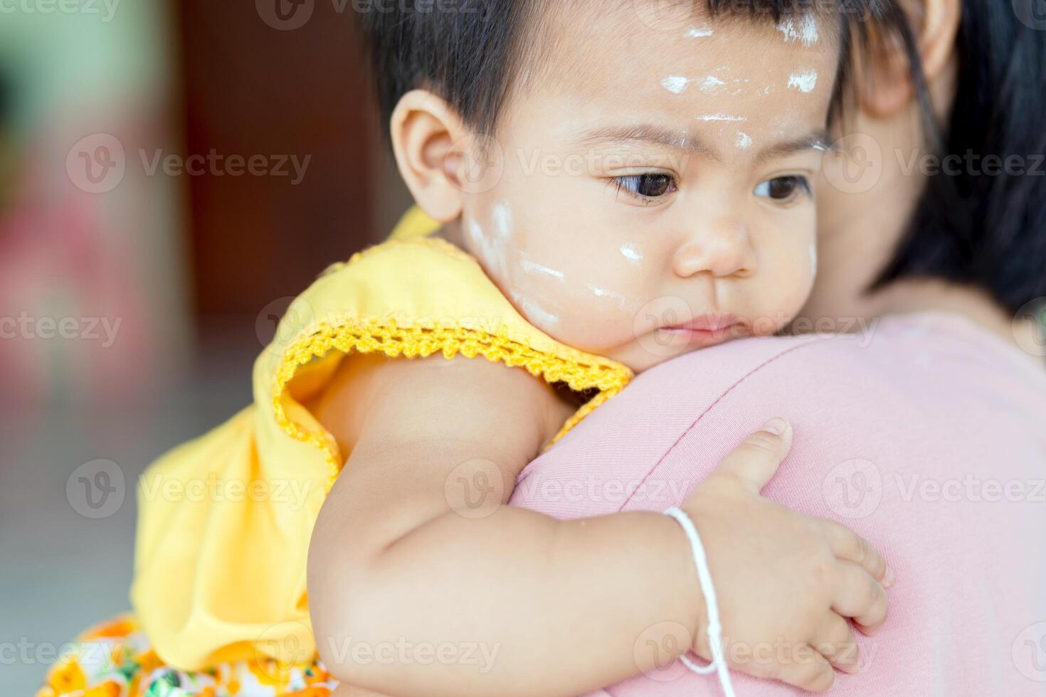 mother holding baby with thanaka paste, portrait baby girl in her mother arms, thai asia kid, baby, child, asian family lifestyle photo