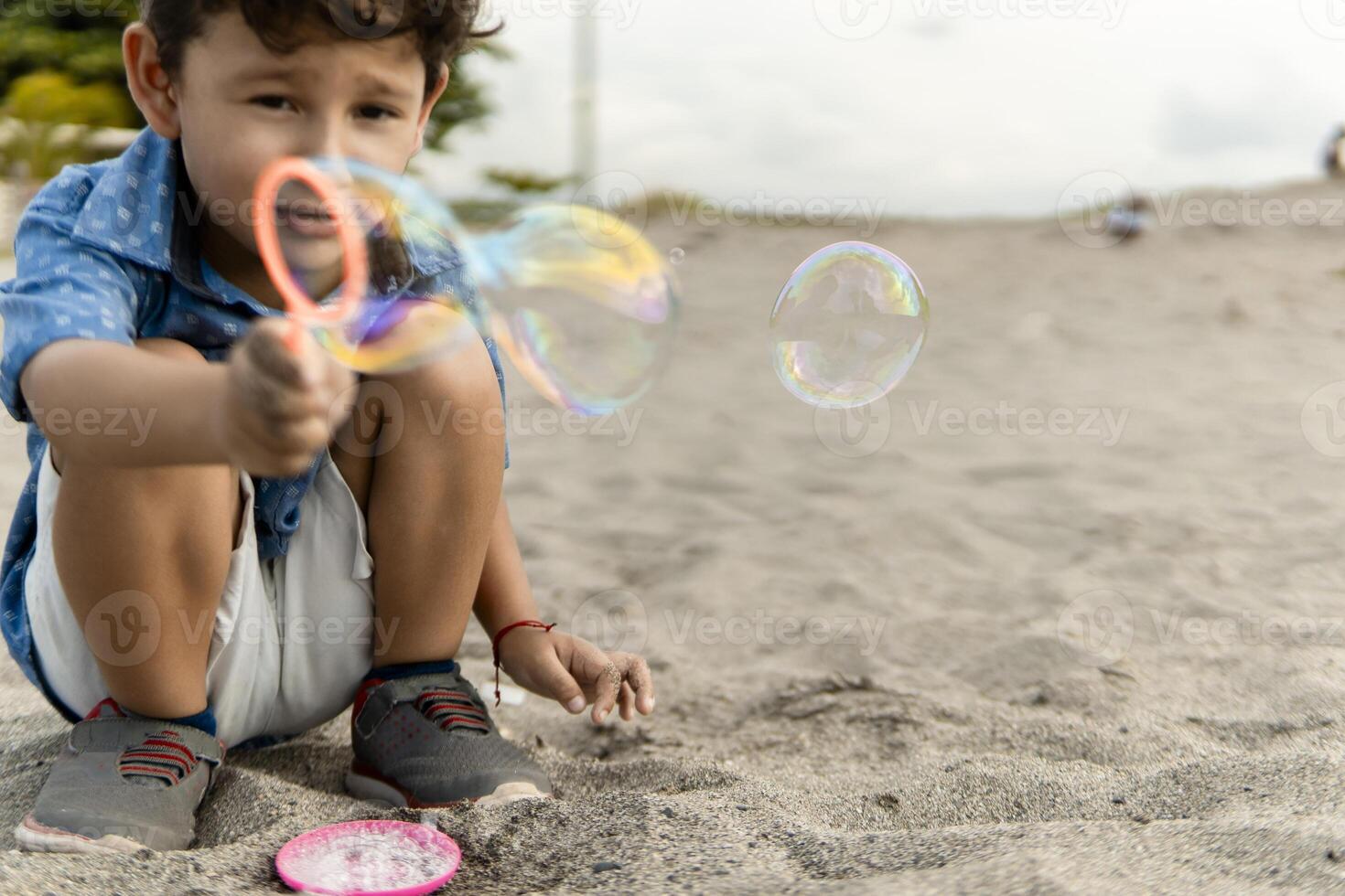 Little boy blowing soap bubbles on the beach photo