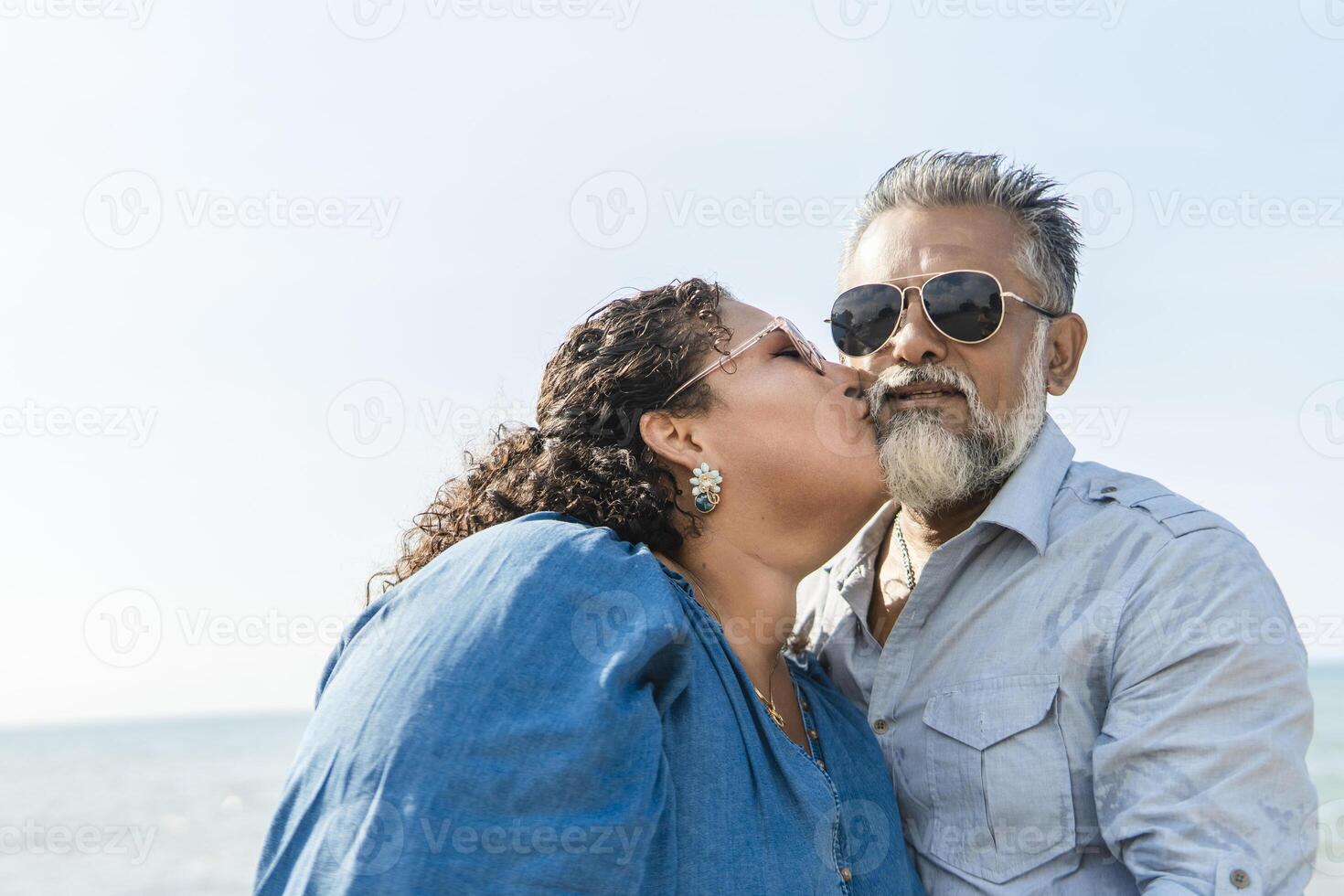 Happy senior couple kissing at the beach on a sunny day photo