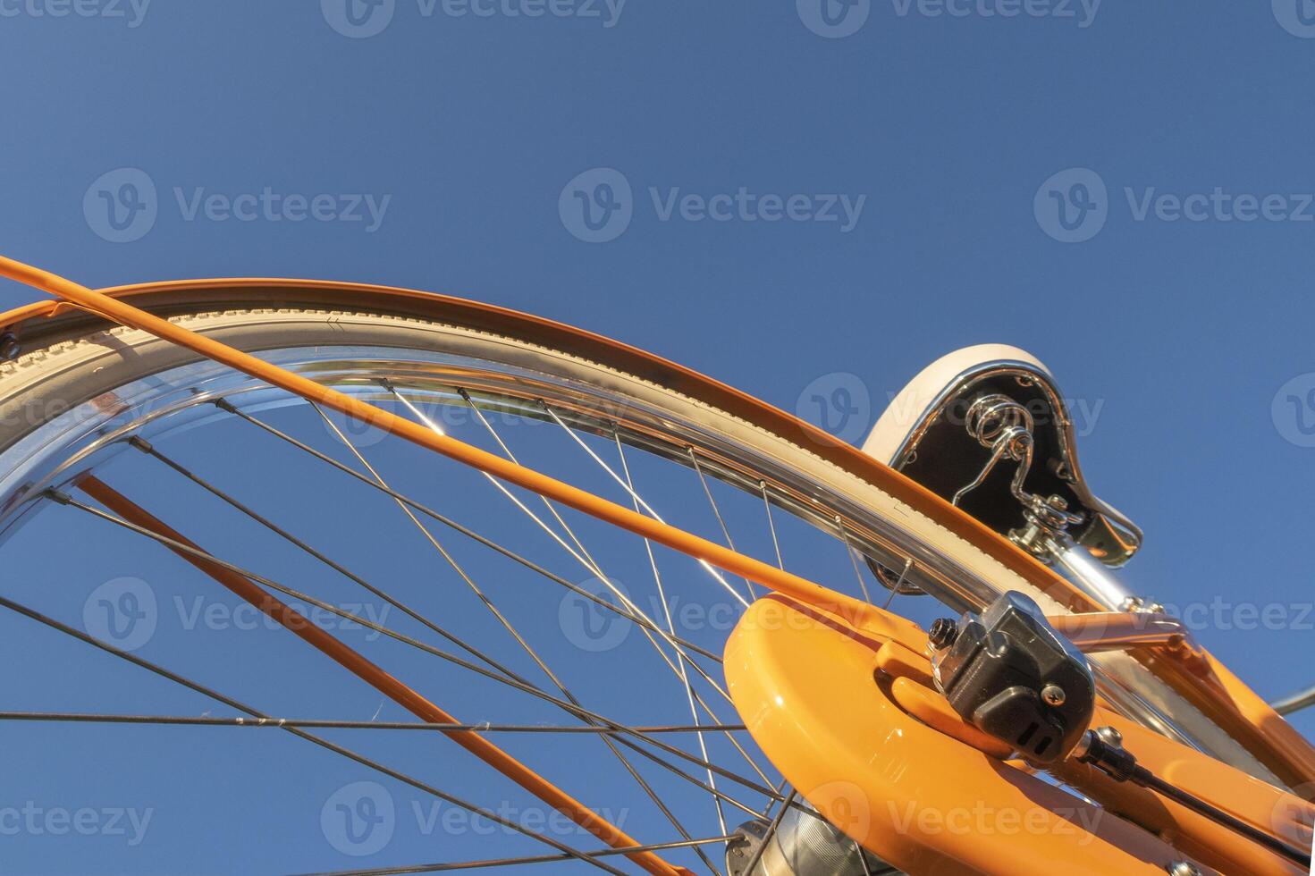 Wheel details of yellow bicycle against blue sky. Closeup view. photo