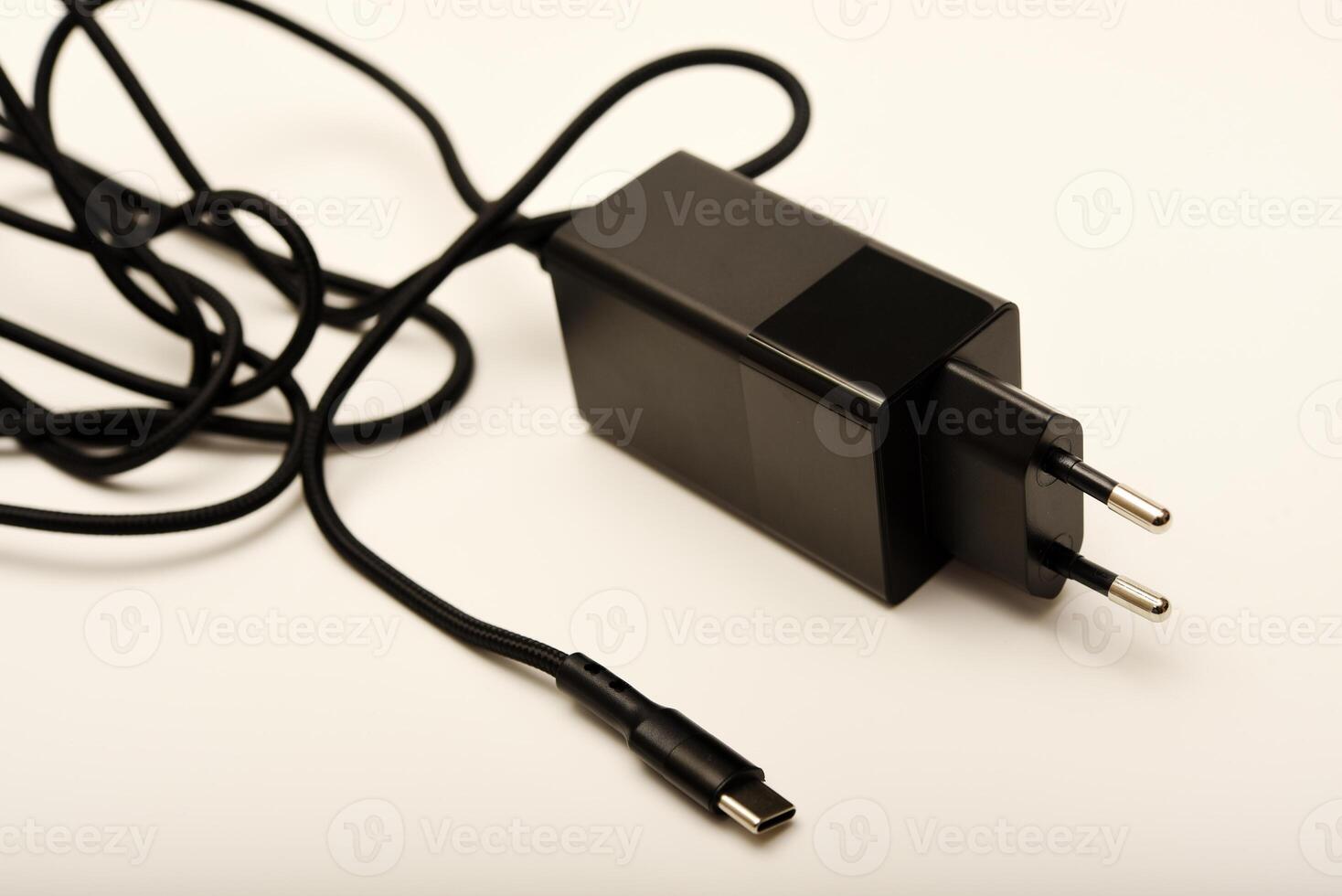 Black fast-charging adapter on white. A new charger for gadgets with a wire. USB charging with a wire. photo