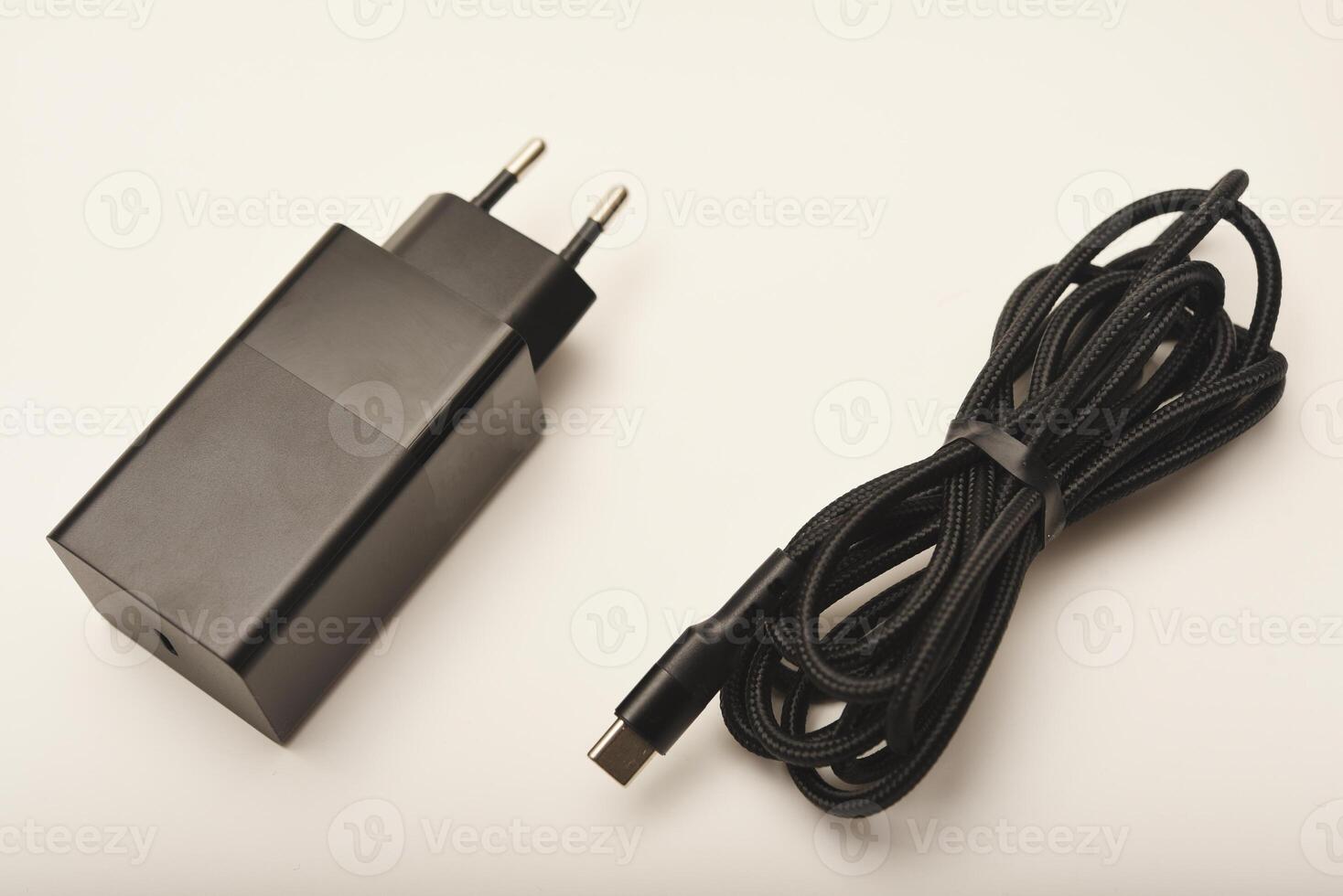 Compact black power adapter on white. A new charger for gadgets with a wire. USB charging with a wire. photo
