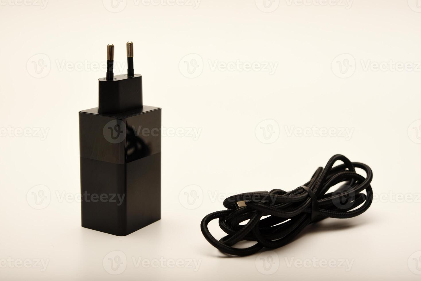 Black charger and straight cable on white. A new charger for gadgets with a wire. USB charging with a wire. photo