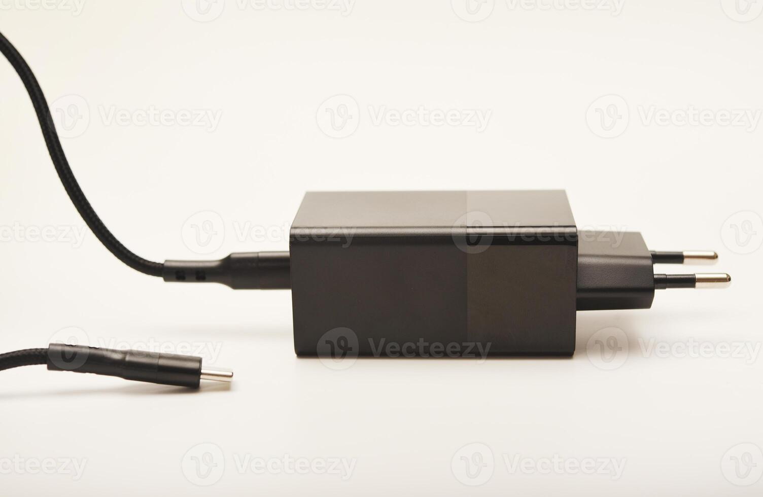 Sleek black charger and wire on white. A new charger for gadgets with a wire. USB charging with a wire. photo