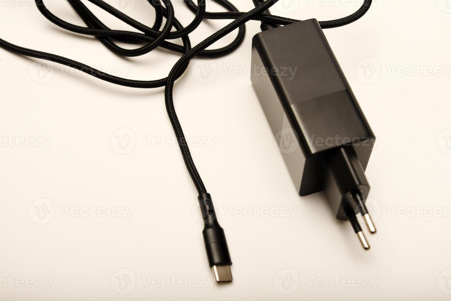 Black charger on white background. A new charger for gadgets with a wire. USB charging with a wire. photo