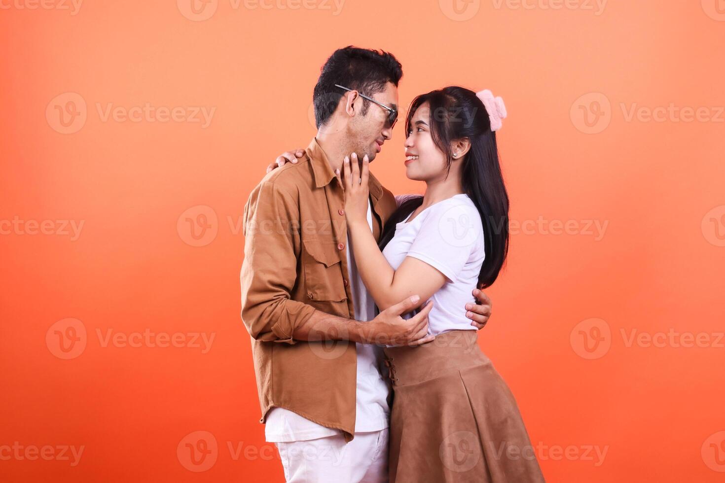 A man and a woman embracing against an orange backdrop in a loving pose photo