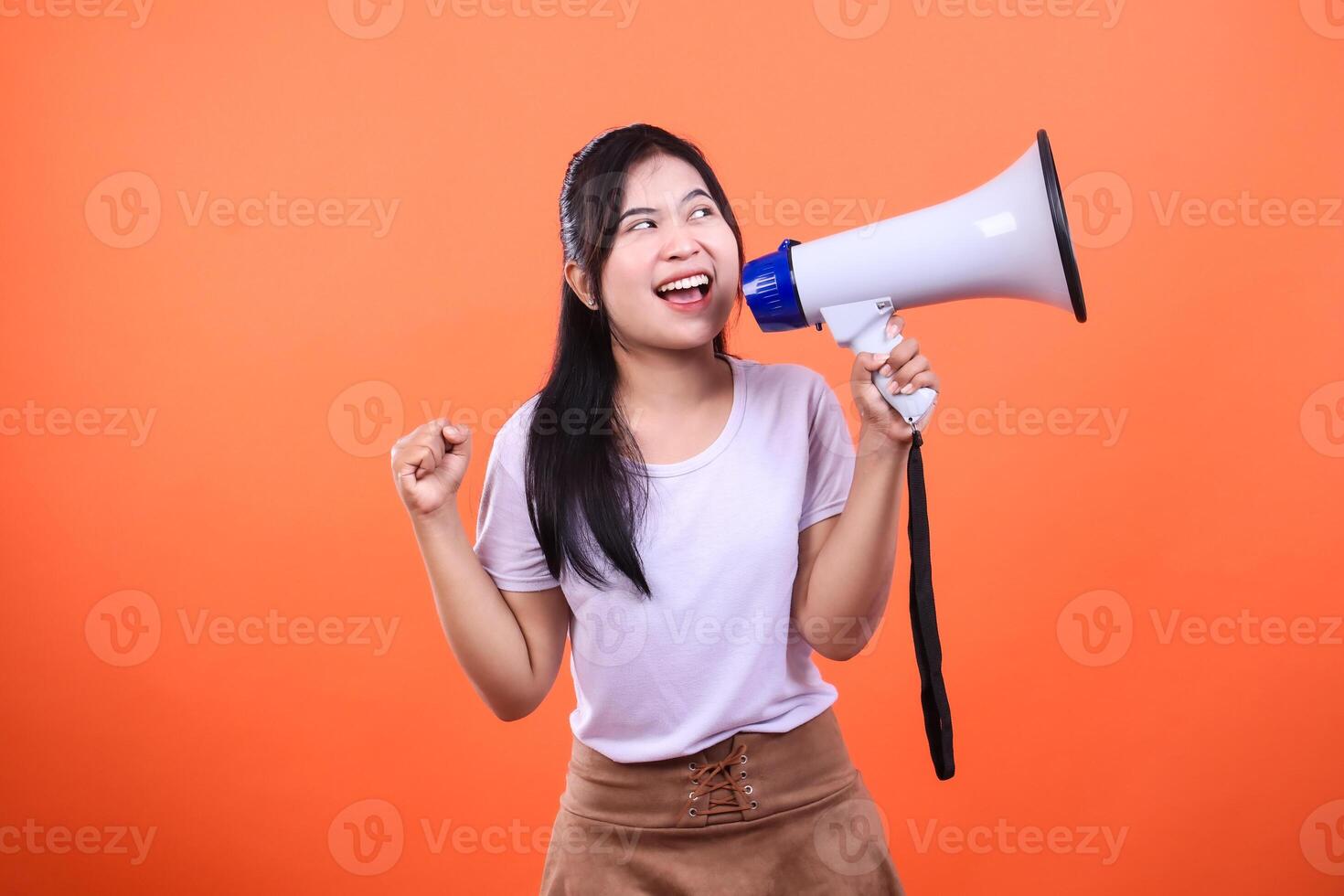 Woman holding a megaphone on a bright orange background ready to make an announcement photo