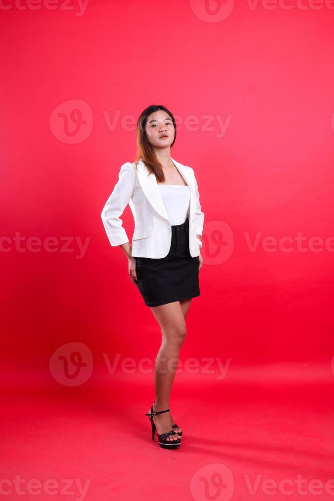 full length beautiful office girl wearing elegant white suit holding buttocks with left hand, standing isolated on red background. for corporate, business, fashion content photo