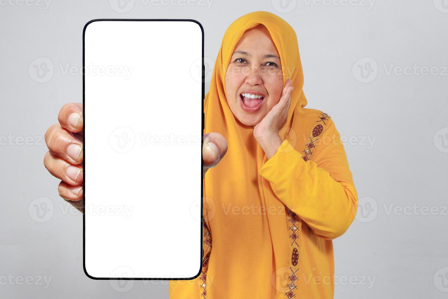 Surprised Muslim woman showing blank smartphone screen to camera photo