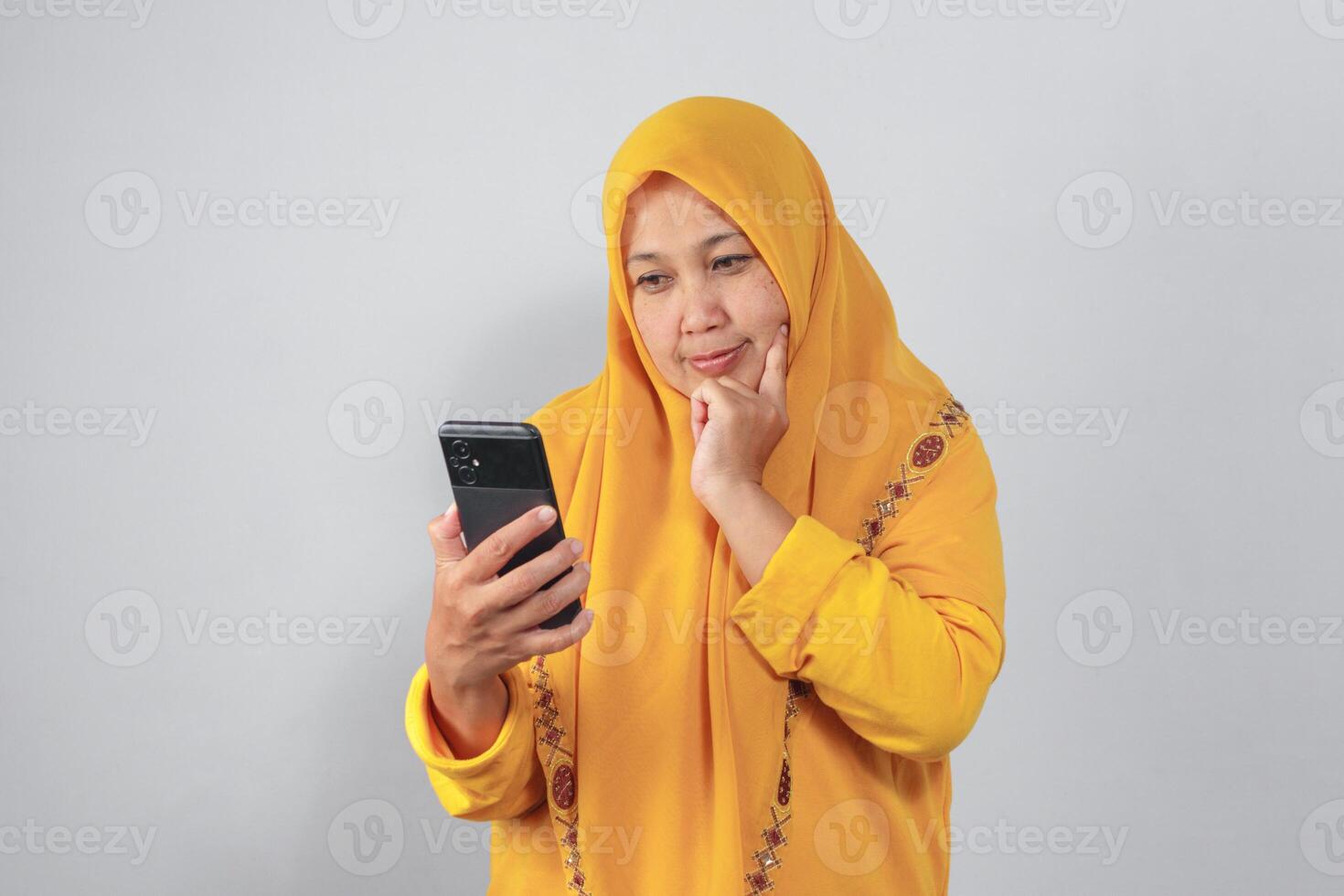Pensive woman in hijab thinking while checking her phone photo