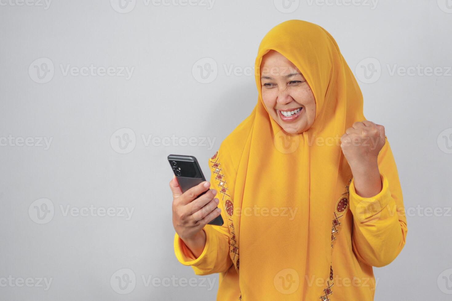 Happy Muslim woman cheering after receiving good news on phone photo