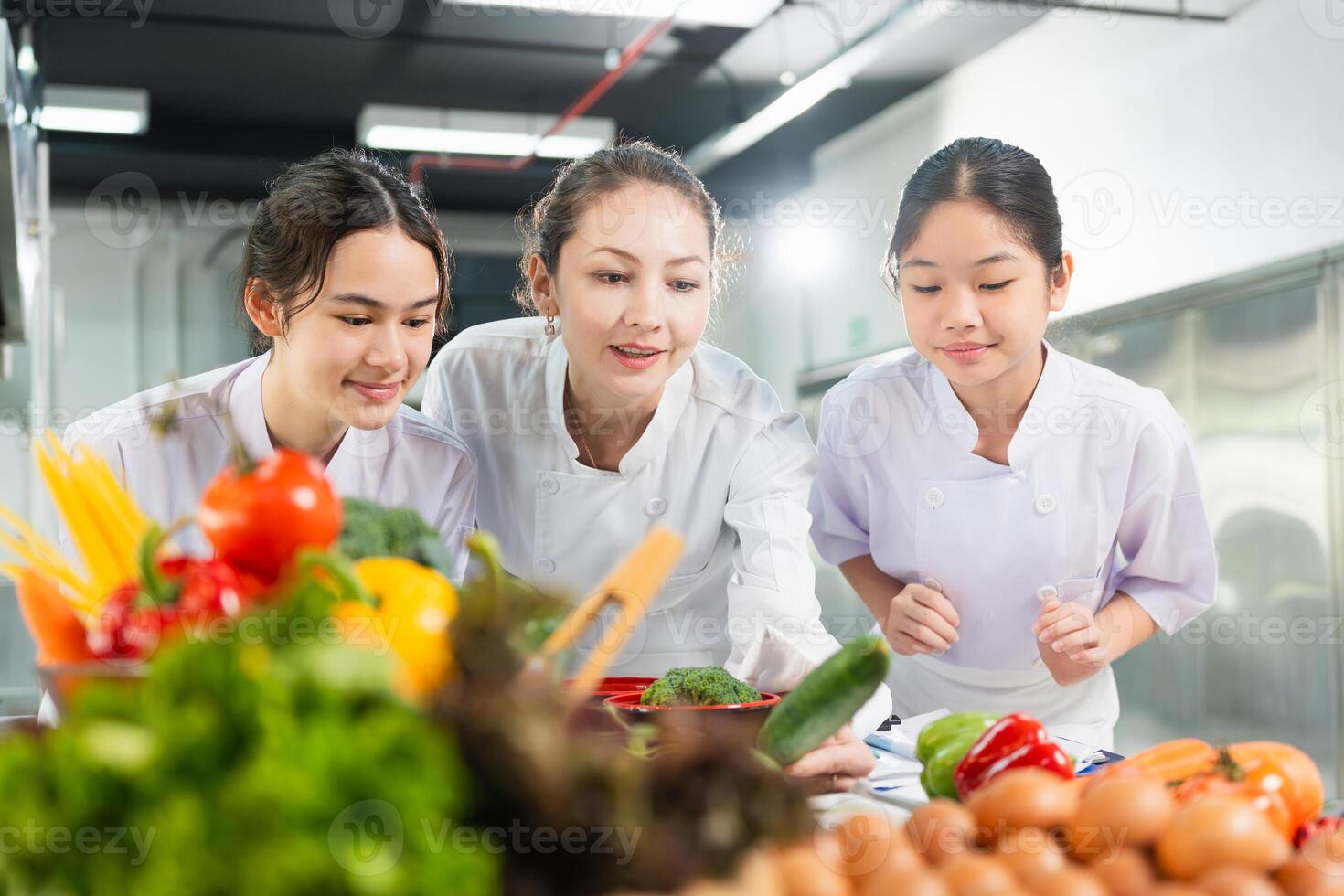 Chef and Students Learning Culinary Skills in Kitchen, Women Preparing Fresh Ingredients for Cooking Class, Professional Chef Mentoring Young Cooks in a Bright Kitchen photo