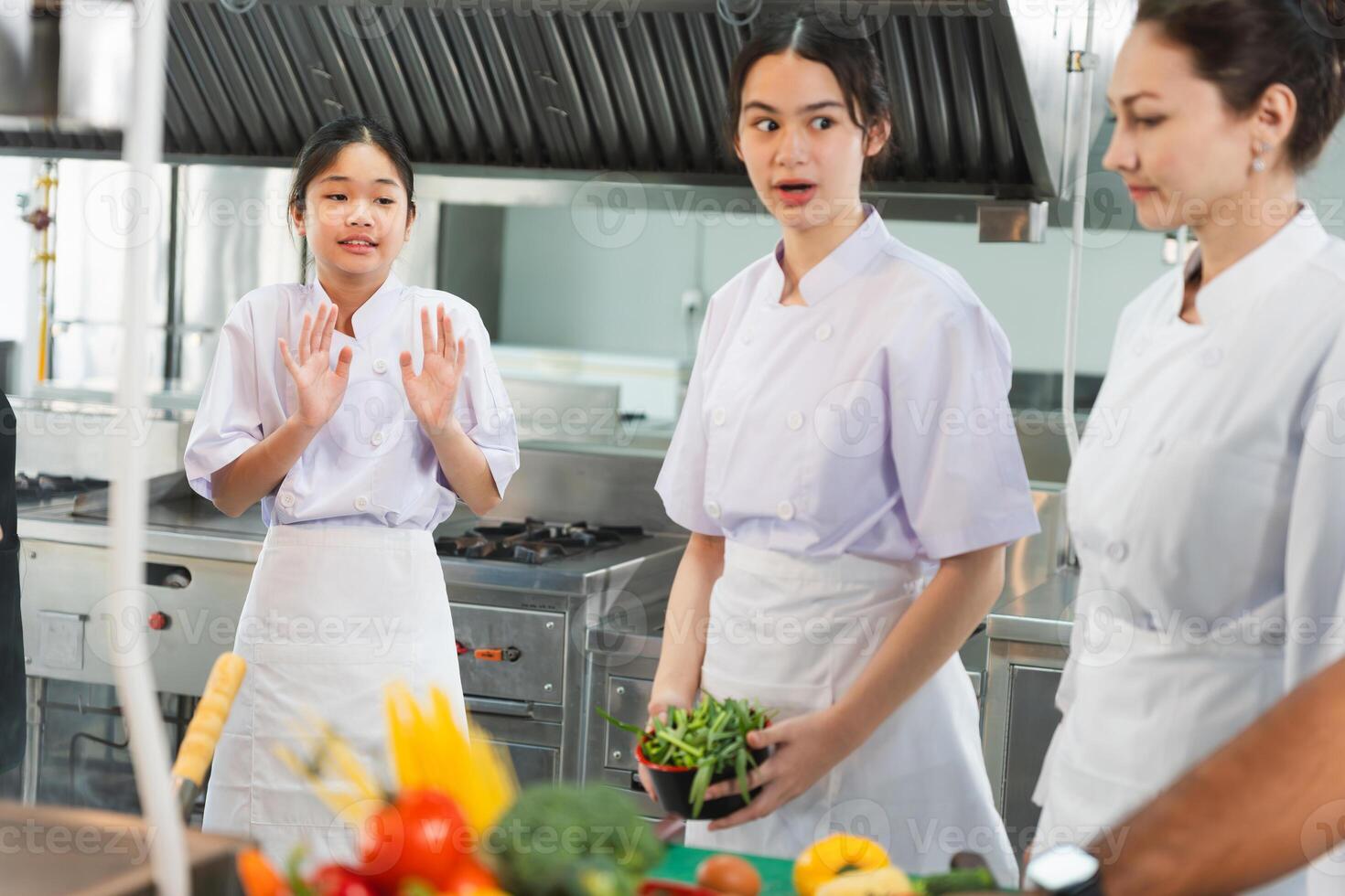 Culinary Students Engaged in Learning with Instructor in Kitchen, Young Chefs Practicing Cooking Techniques with Fresh Ingredients, Women in Chef Uniforms Discussing Food Preparation in Kitchen photo