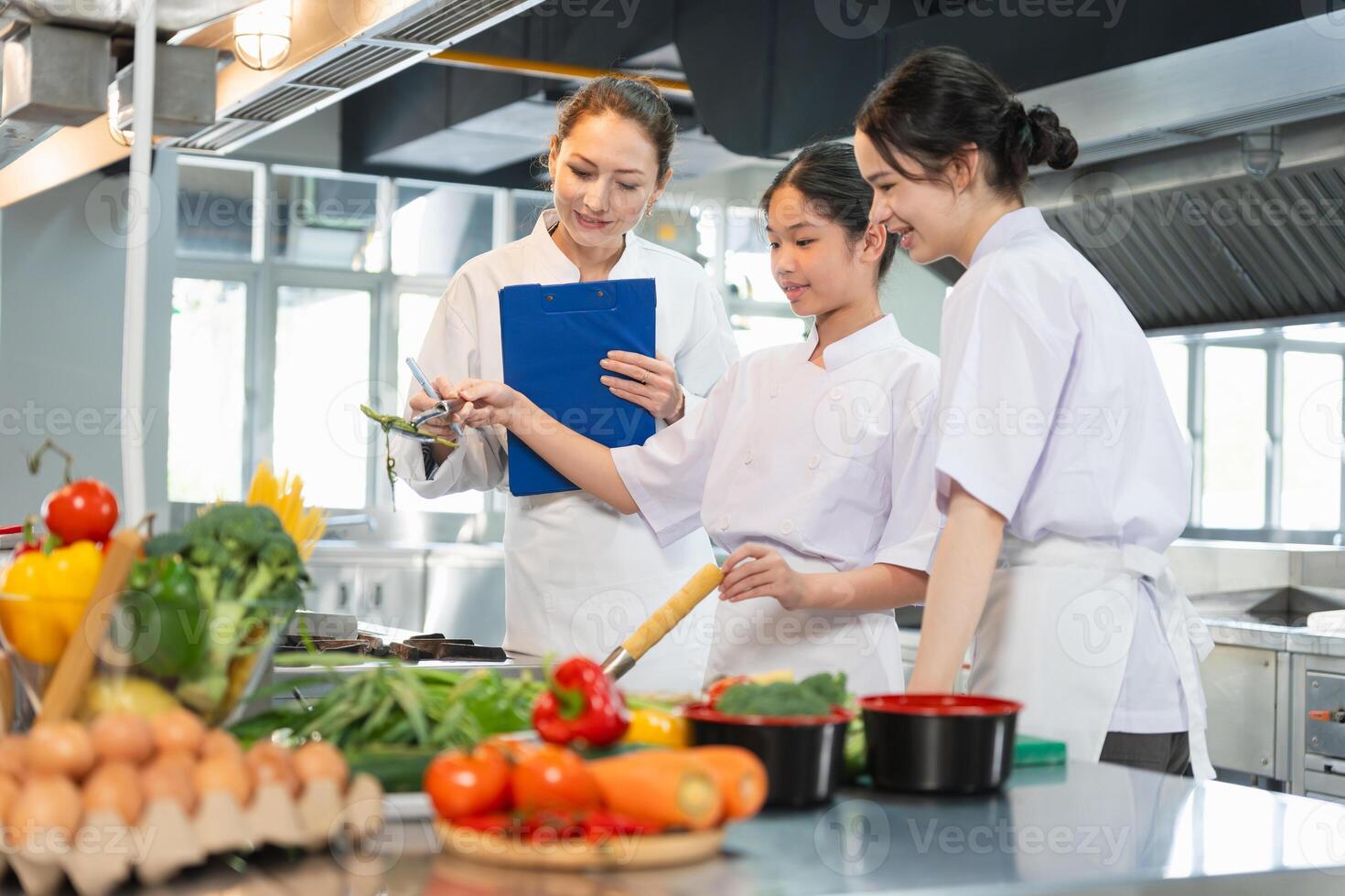 Young Chefs Learning to Cook with Fresh Ingredients, Culinary Instructor Guides Students in a Professional Kitchen, Women in Chef Uniforms Preparing Food in a Commercial Kitchen photo