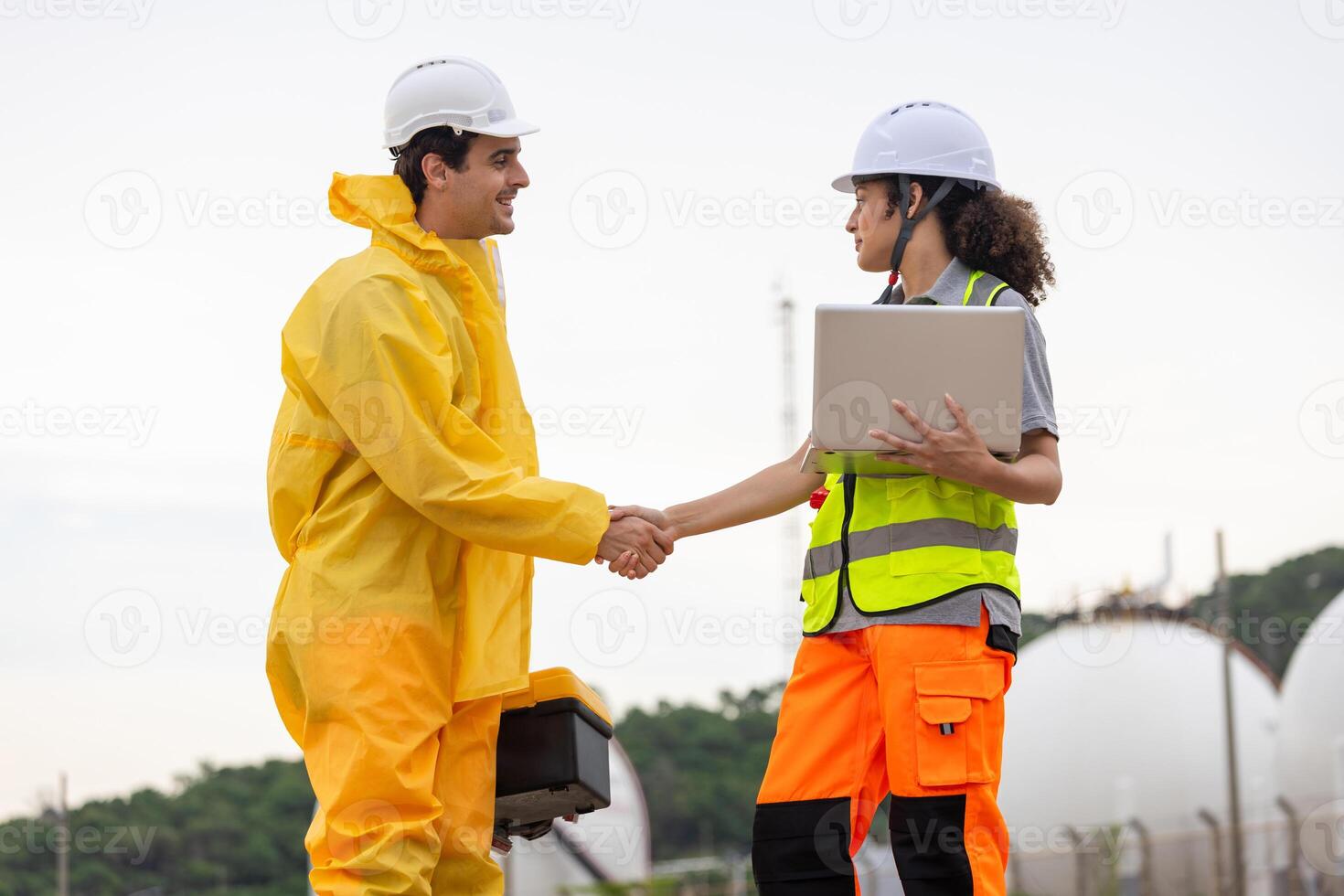 Environmental Workers Inspecting Industrial Site, Team in Protective Gear Surveying Contaminated Area, Engineer and Environmental Worker Shaking Hands at a Chemical Plant photo