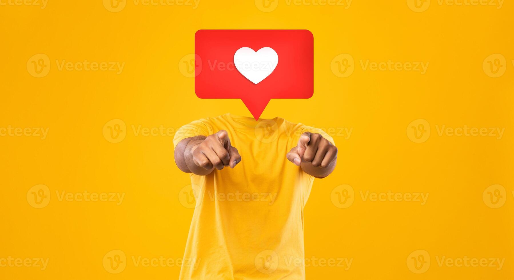 A person wearing a yellow shirt points toward the viewer in a vibrant setting filled with a bright yellow background. Instead their head is heart icon symbolizing likes and affection in social media. photo