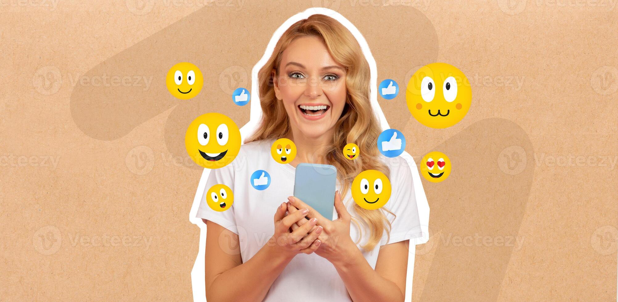 A woman with long blonde hair smiles happily while holding her smartphone. She is engaged in chatting and posting on social media. Colorful emojis surround her, enhancing the cheerful mood. photo