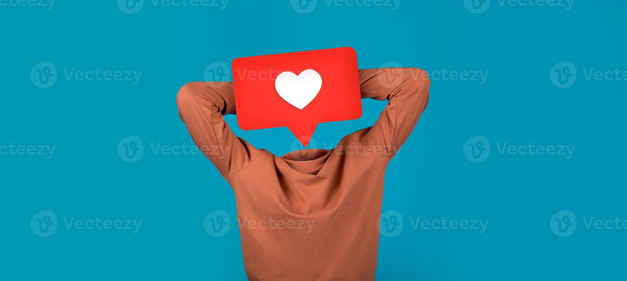 A person sits back with arms behind their head, appearing relaxed. Above them is a prominent red speech bubble with a white heart icon, showcasing a connection to social media. photo