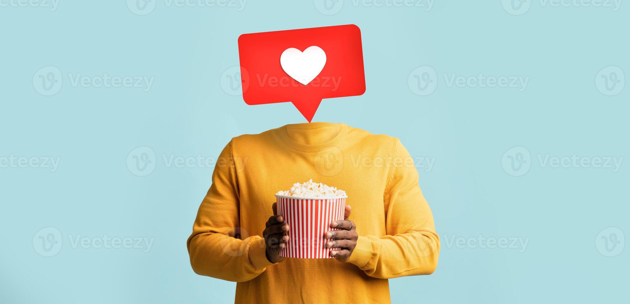 A person holds a bucket of popcorn while a heart icon appears above where their head should be. This visual represents social media interaction and engagement in a playful way. photo