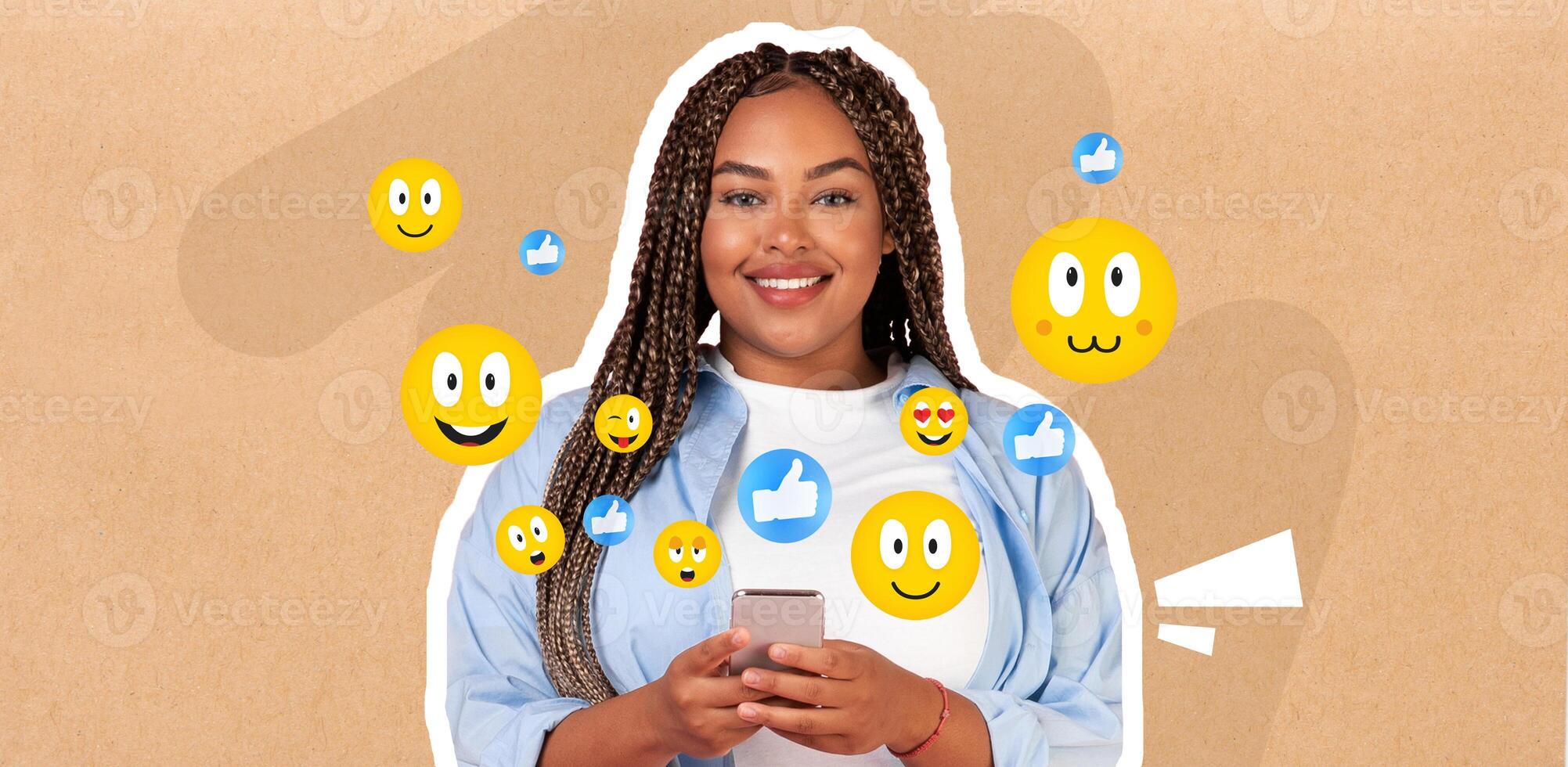 A young African American woman smiles while texting on her smartphone, surrounded by various playful emoji icons. She seems engaged in lively conversation, expressing joy through digital interaction. photo