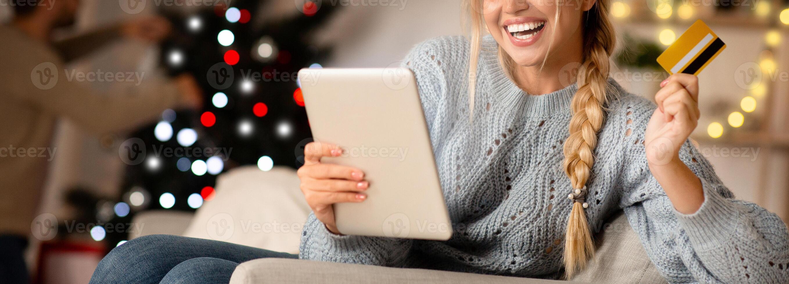 Excited lady shopping online on Christmas, using digital tablet and credit card, xmas sales concept photo