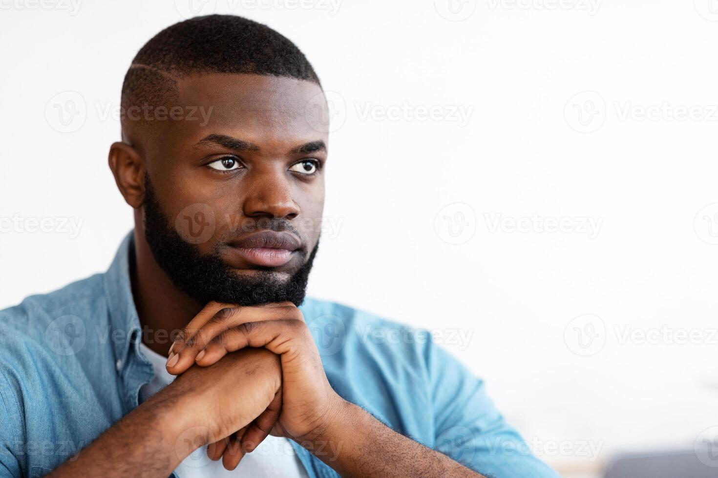 Closeup Portrait Of Serious Handsome Black Man Sitting With Pensive Face Expression, Young African American Guy Thinking About Something, Waiting For Inspiration, Leaning Chin On Hands, Copy Space photo