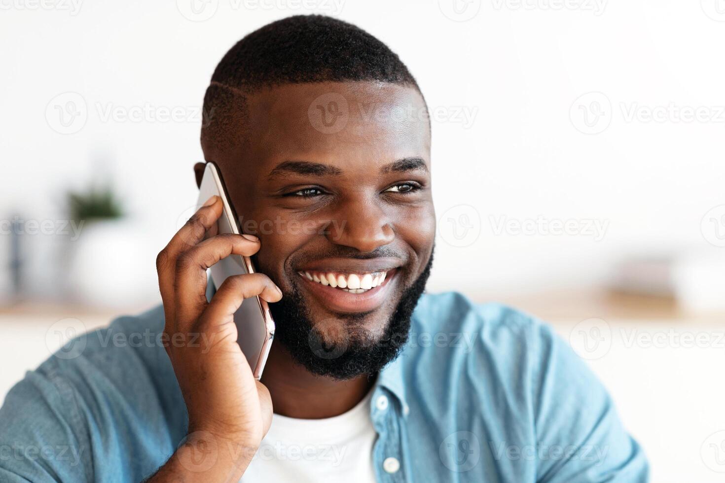 Pleasant Call. Positive Millennial Black Man Talking On Mobile Phone And Smiling, Cheerful African American Guy Enjoying Phone Conversation, Looking Aside With Pleased Face Expression, Closeup photo