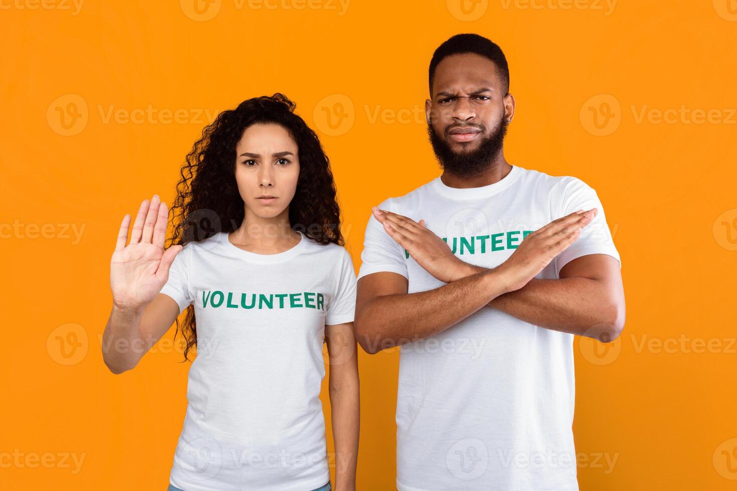 Stop It. Two Multicultural Volunteers Female And Male Gesturing Stop And Crossing Hands Looking At Camera Forbidding Something Standing Over Yellow Background. Studio Shot photo