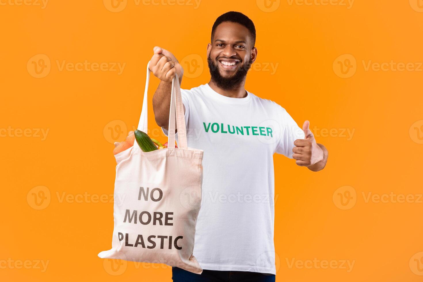 No More Plastic. Cheerful Volunteer Man Holding Eco Bag With Groceries Gesturing Thumbs Up Standing On Yellow Studio Background. Ecology And Consumerism, I Like Eco-Friendly Lifestyle Concept photo