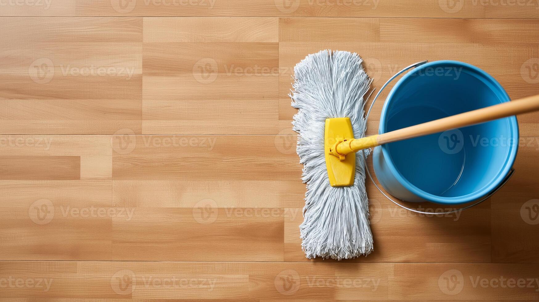 A person is mopping a wooden floor with a grey mop and a blue bucket nearby, cleaning diligently. photo