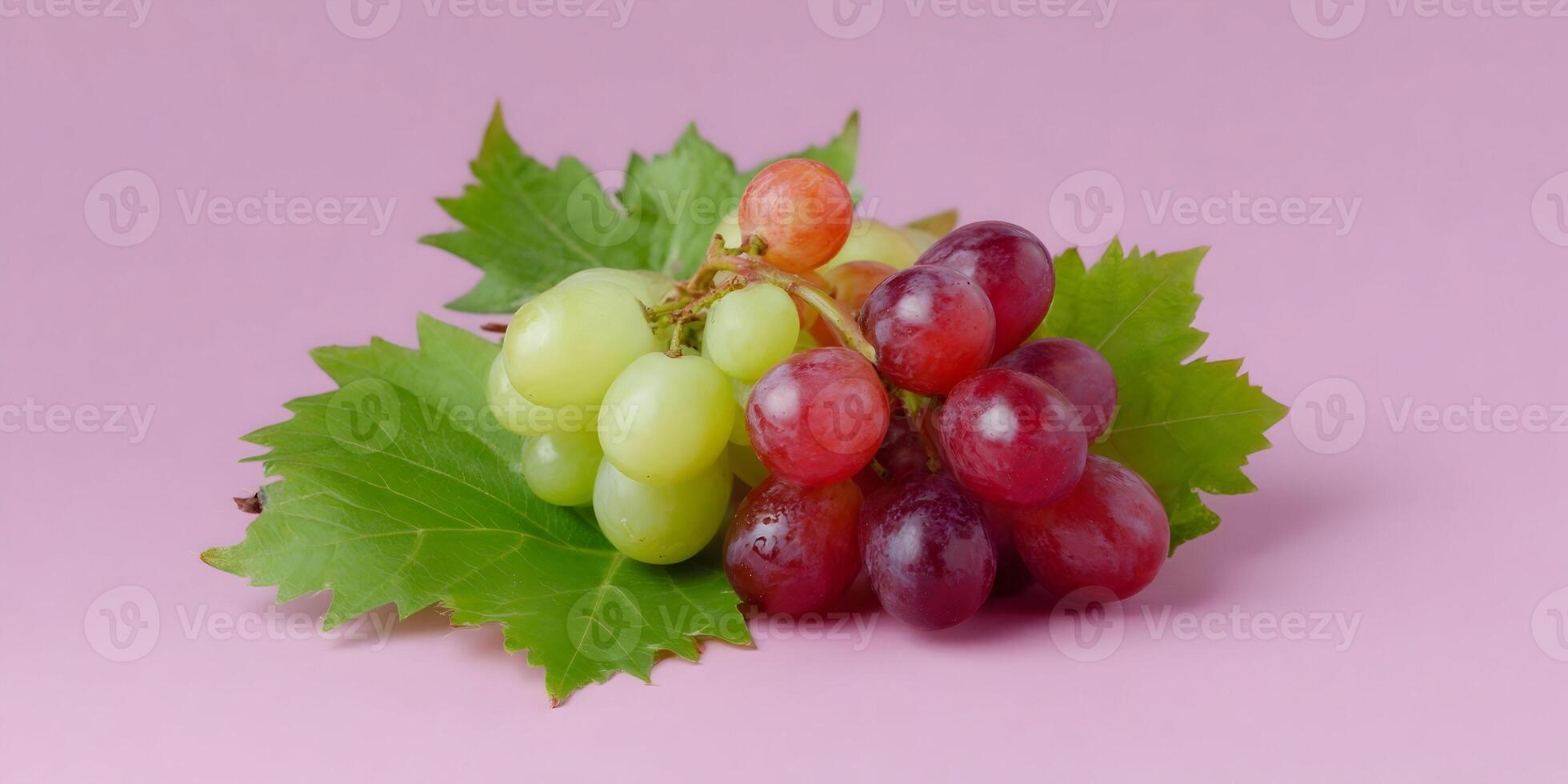 Green and Red Grapes with Vine Leaves on Pink Background photo