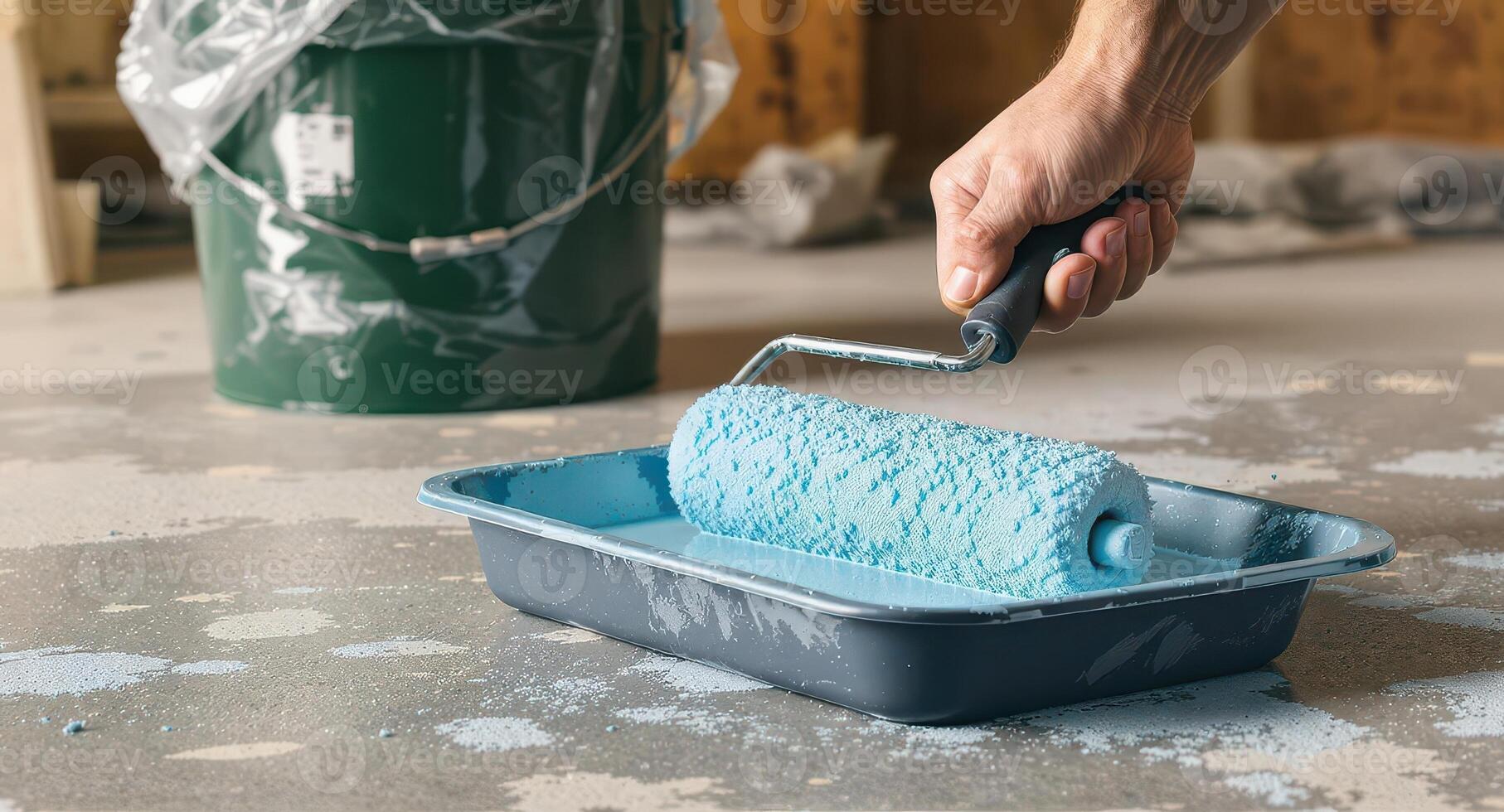 Man hand dipping paint roller into light blue paint tray for home renovation project photo