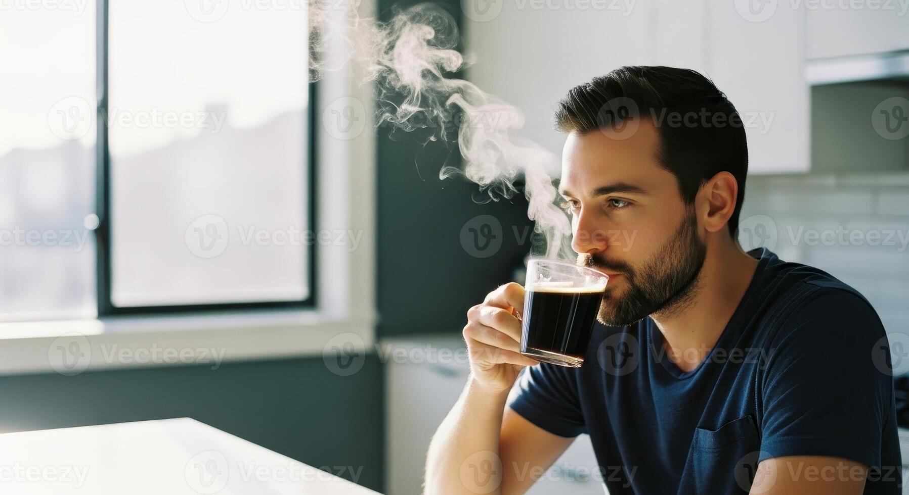 Bearded man enjoying hot black coffee with steam in a bright modern kitchen photo