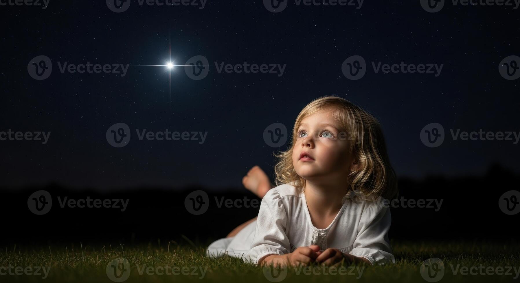 Young child looking up at a bright shining star in the dark night sky with wonder photo