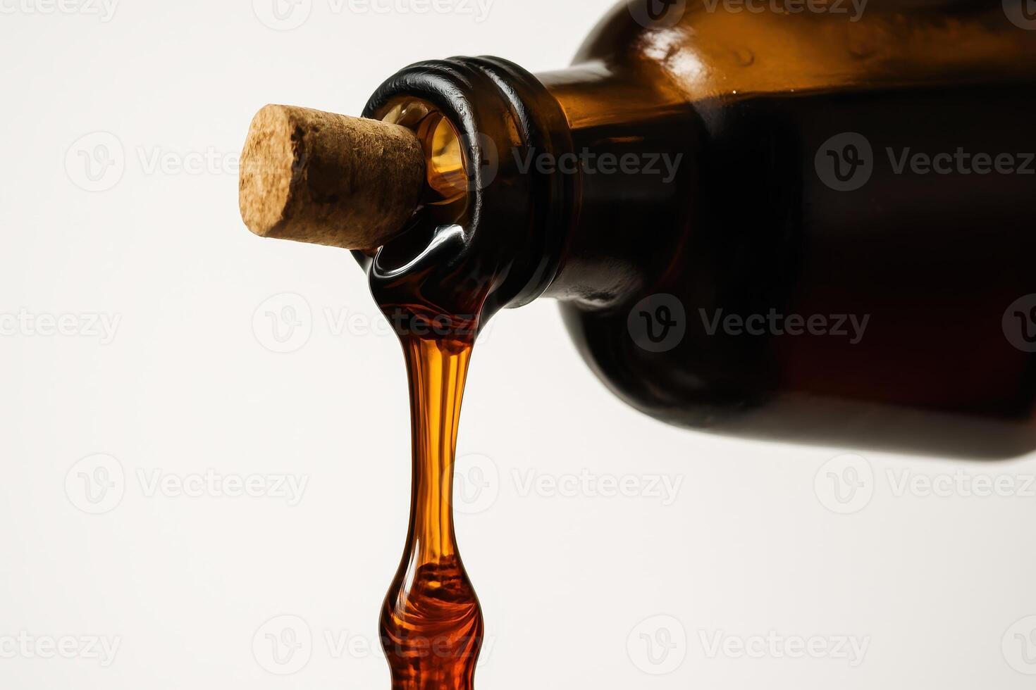 Close up of viscous amber syrup pouring from a rustic glass bottle with a cork photo