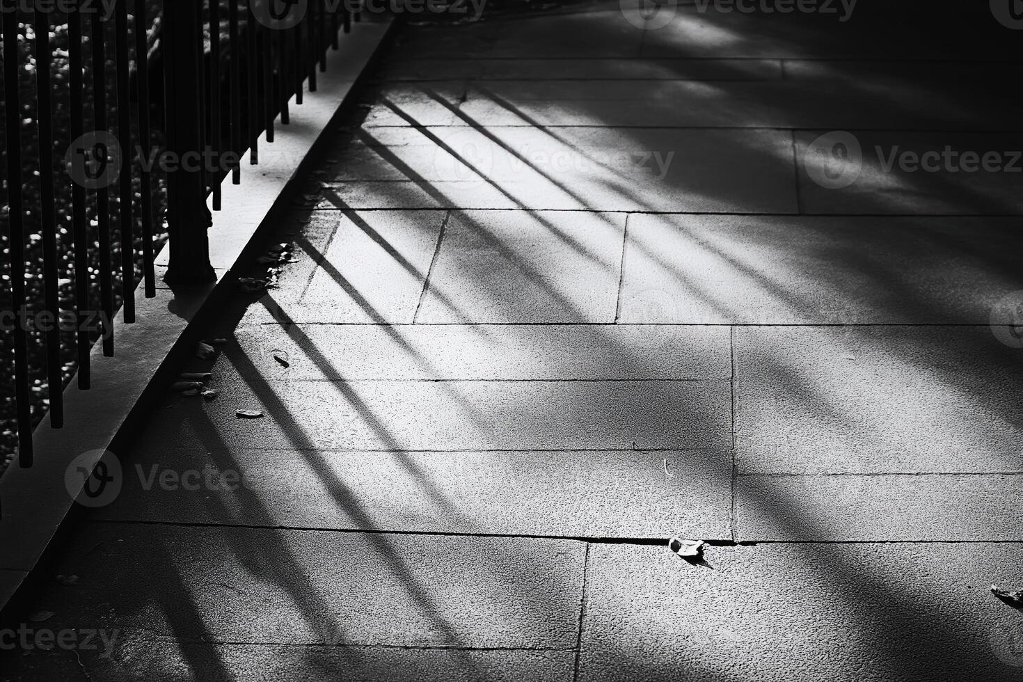 Shadows of railings creating stripes on sidewalk in black and white photo