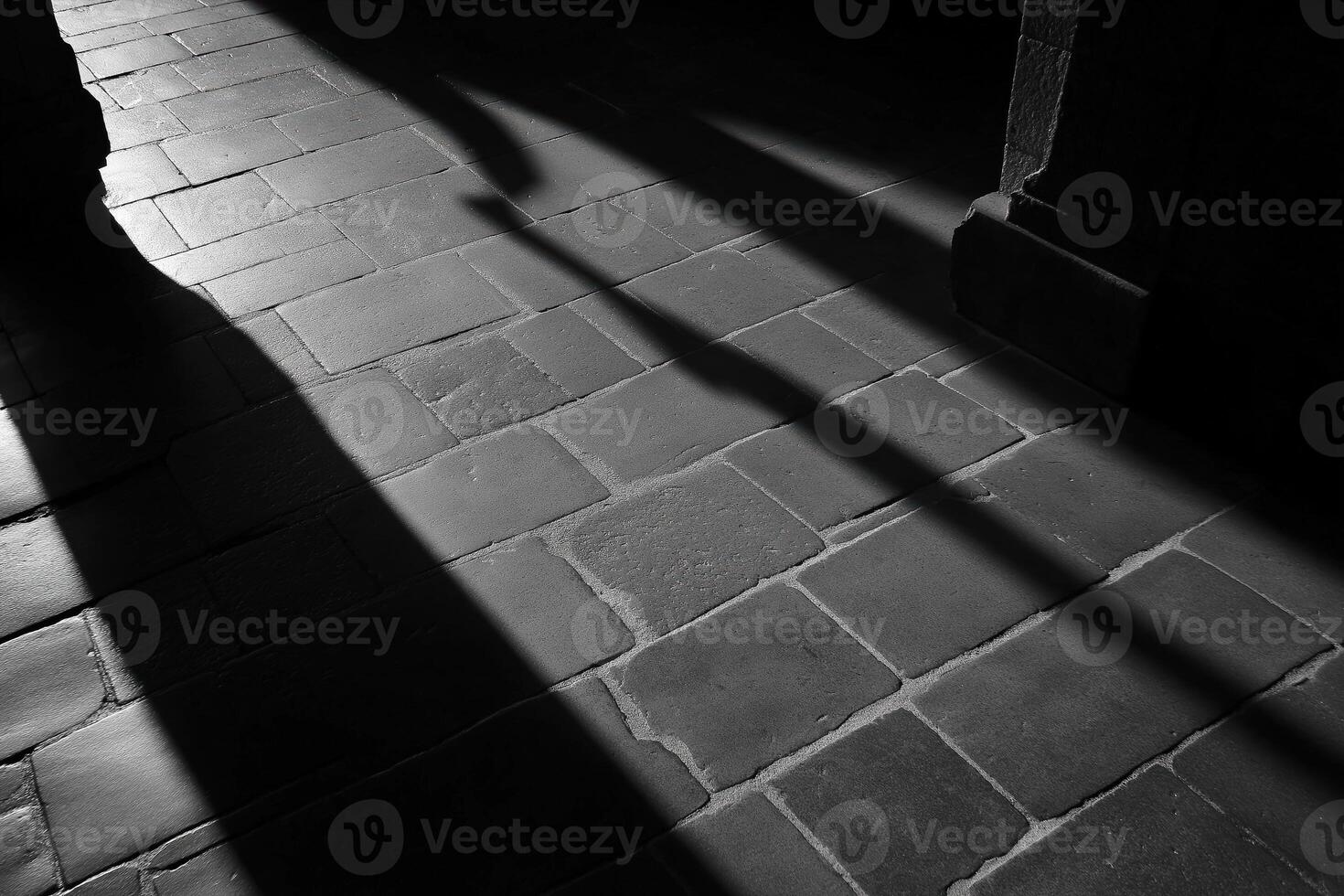 Shadows stretching across stone tiled floor in black and white photo