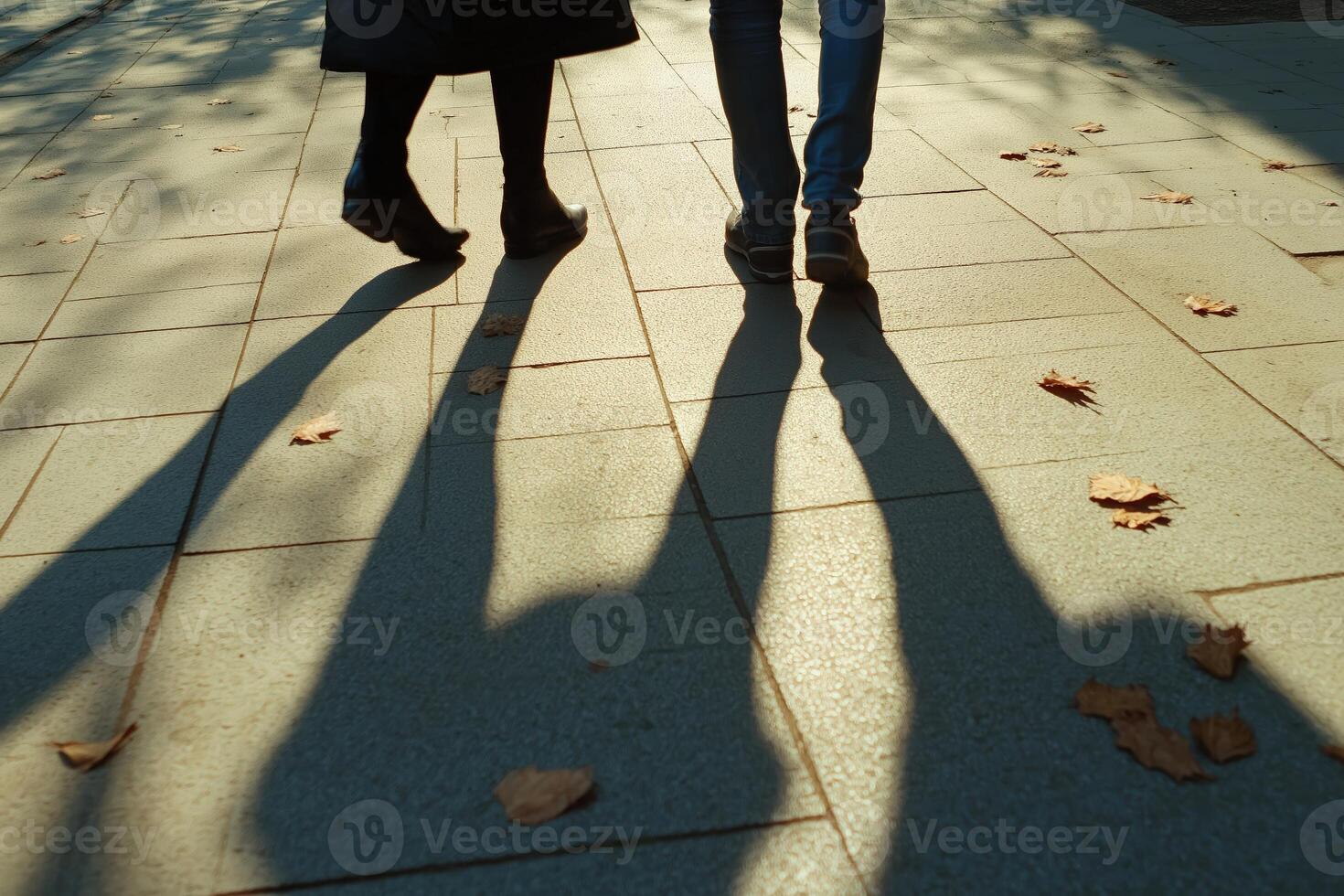 Couple walking together and casting long shadows on pavement in autumn photo