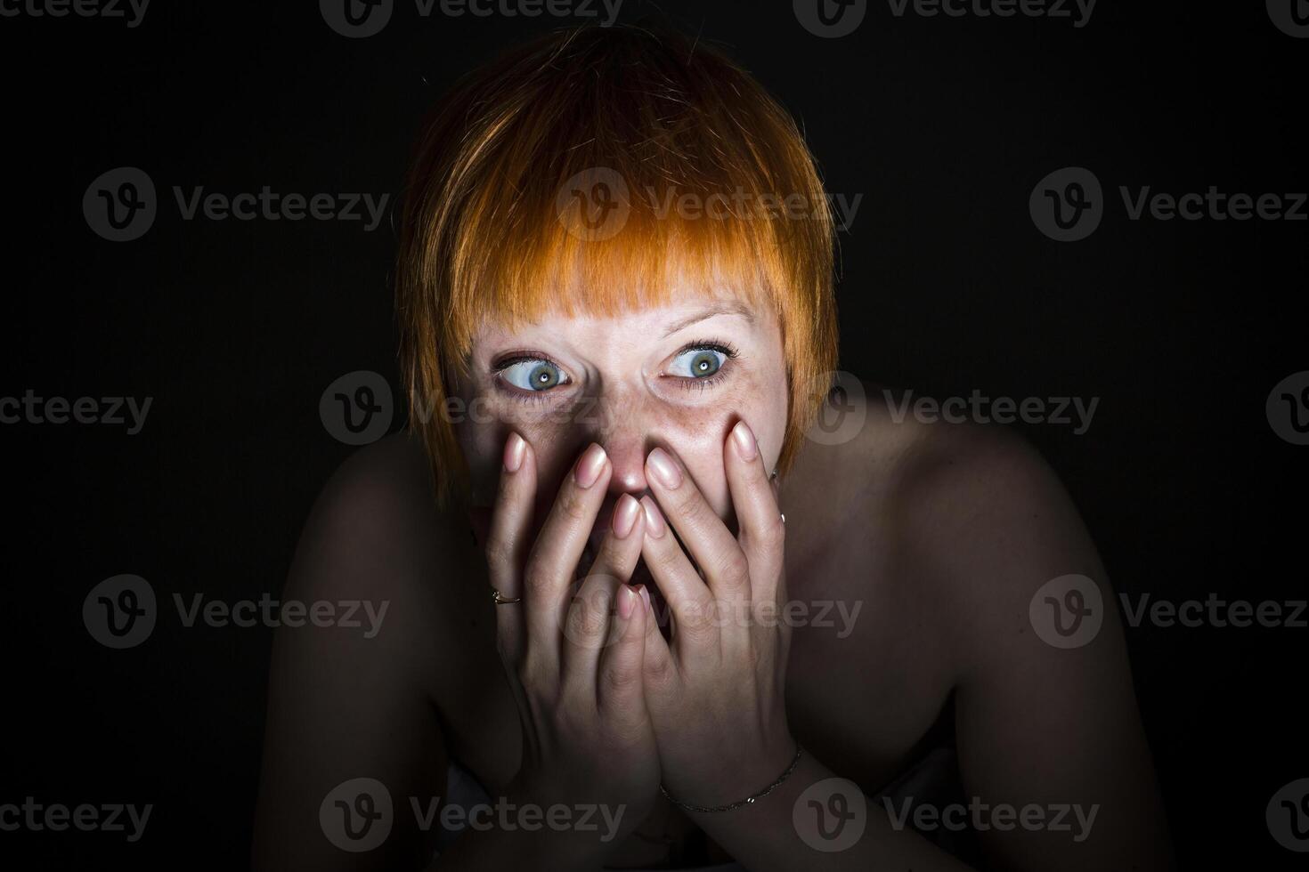 moscow, russia, 14.06.2017 A woman with red hair is looking at the camera with her hands covering her face photo