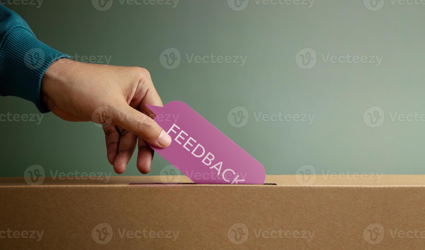 Hand putting feedback card in box symbolizing customer review, survey response, and constructive evaluation photo