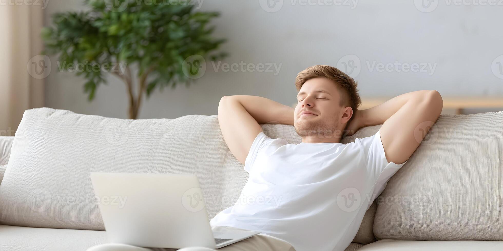Young Man Relaxing on Beige Sofa with Laptop Eyes Closed photo